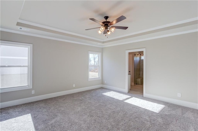 empty room featuring ornamental molding, a tray ceiling, ceiling fan, and light colored carpet