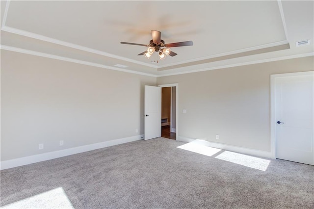 carpeted spare room featuring ceiling fan, ornamental molding, and a tray ceiling