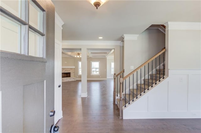 entryway featuring crown molding, dark wood-type flooring, and a fireplace