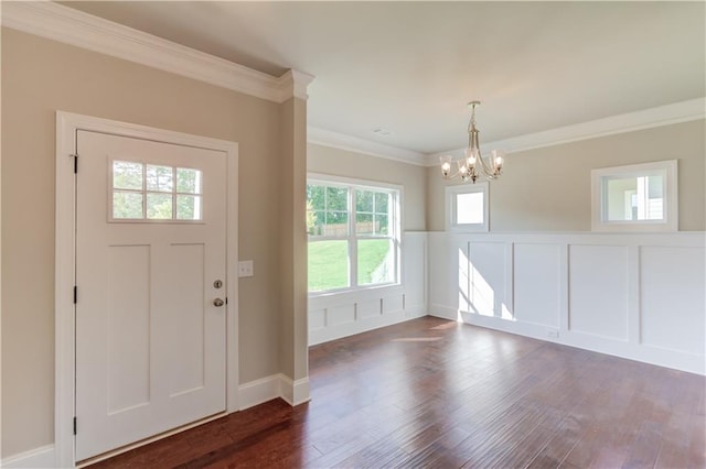 entrance foyer with dark hardwood / wood-style flooring, ornamental molding, and a chandelier