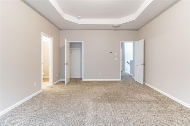 unfurnished bedroom with a raised ceiling, light carpet, visible vents, and baseboards