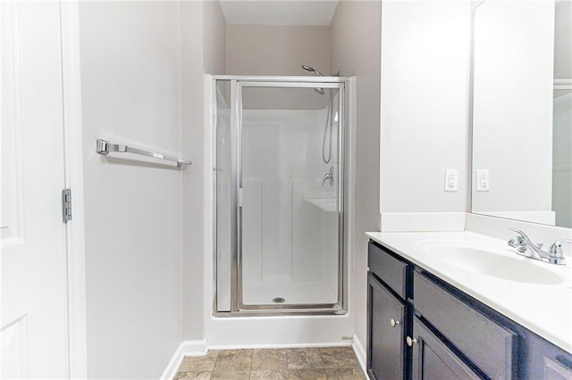 full bathroom with a stall shower, vanity, and baseboards