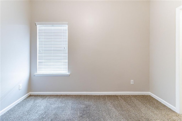 spare room featuring light carpet and baseboards