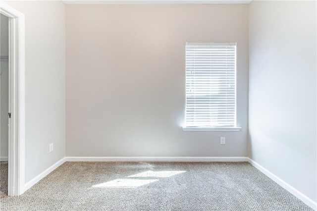 carpeted empty room featuring baseboards