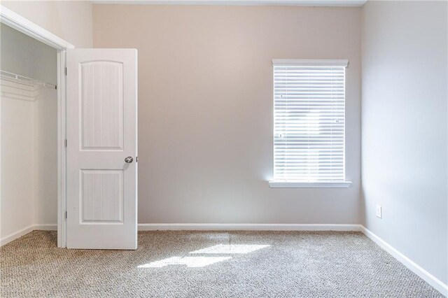 unfurnished bedroom with light carpet, baseboards, and a closet