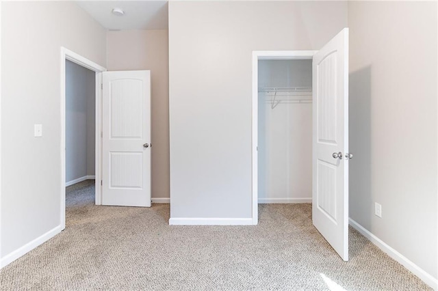 unfurnished bedroom with a closet, carpet flooring, and baseboards