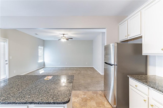 kitchen with light carpet, a ceiling fan, freestanding refrigerator, and white cabinets