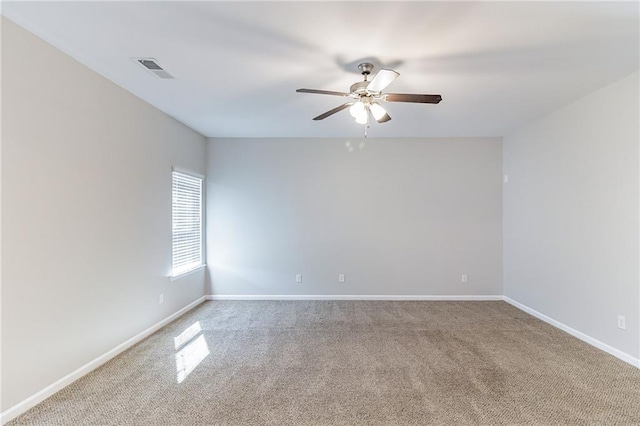 carpeted spare room with a ceiling fan, visible vents, and baseboards