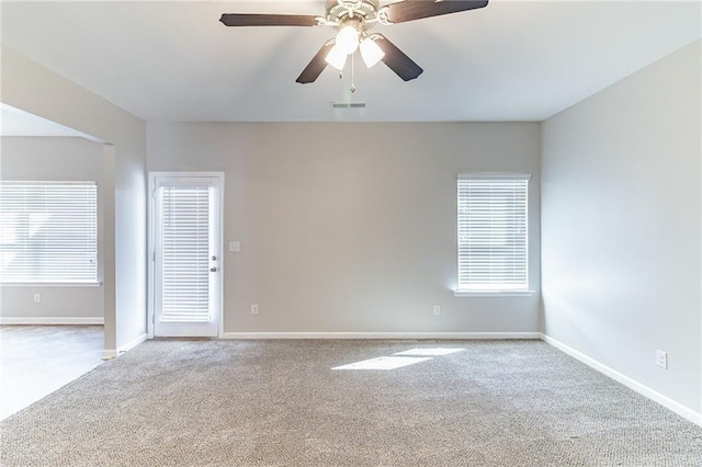 carpeted empty room featuring a healthy amount of sunlight, baseboards, and visible vents