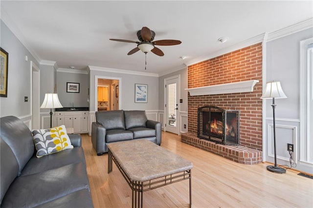 4423 Windsor Oaks Cir, Marietta, GA 30066 - living room with a ceiling fan, light wood-type flooring, a fireplace, crown molding, and a decorative wall