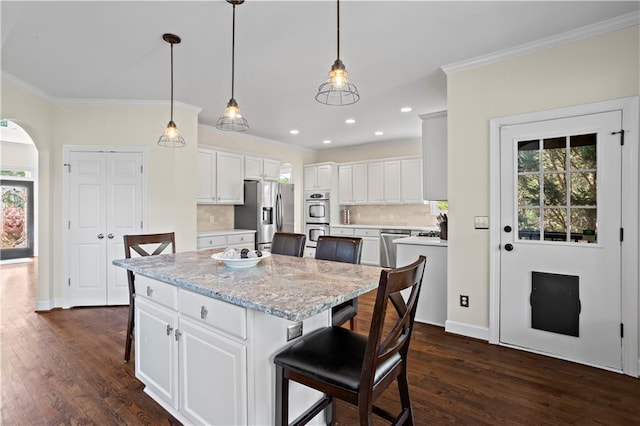 410 Hickory Fairway Ct, Woodstock, GA 30188 - kitchen featuring appliances with stainless steel finishes, a center island, ornamental molding, tasteful backsplash, and dark wood finished floors
