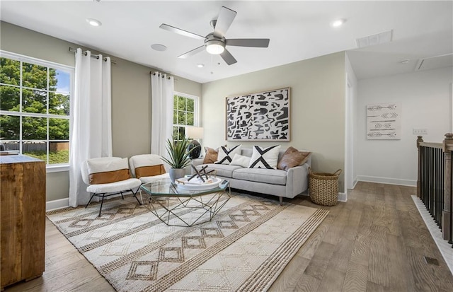 sitting room with a ceiling fan, visible vents, baseboards, and wood finished floors