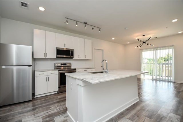 kitchen with stainless steel appliances, an island with sink, hardwood / wood-style floors, and sink