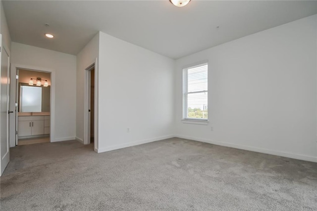 unfurnished bedroom with light carpet and connected bathroom