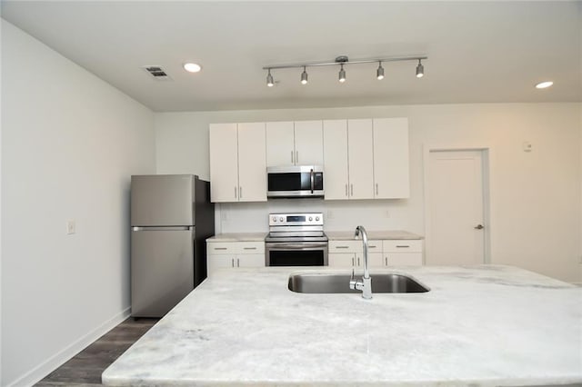 kitchen with light stone counters, white cabinets, dark wood-type flooring, sink, and appliances with stainless steel finishes