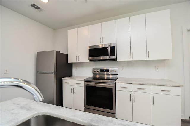 kitchen featuring stainless steel appliances, sink, and white cabinetry