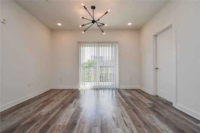 empty room with dark wood-type flooring and a chandelier