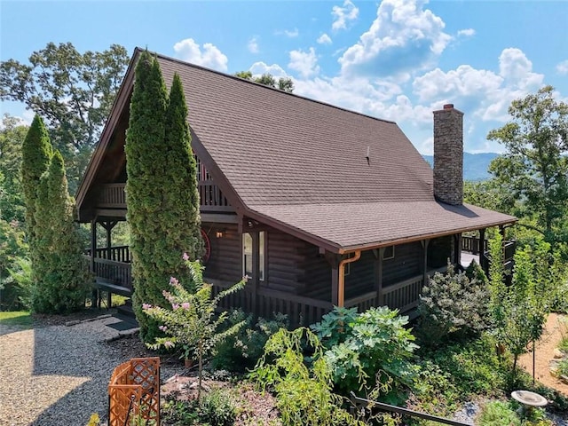 back of house featuring a chimney and a shingled roof