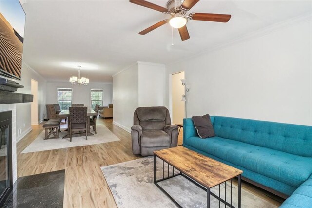 living room featuring ceiling fan with notable chandelier, light hardwood / wood-style flooring, and crown molding