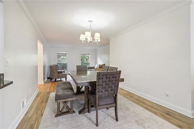 dining area featuring a chandelier, crown molding, and light hardwood / wood-style flooring