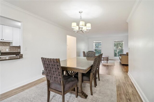 dining area featuring light hardwood / wood-style flooring, crown molding, and an inviting chandelier