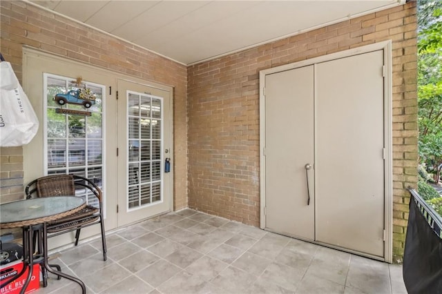 entryway featuring light tile patterned floors and brick wall