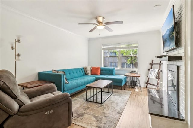 living room featuring ceiling fan, light hardwood / wood-style flooring, crown molding, and a fireplace