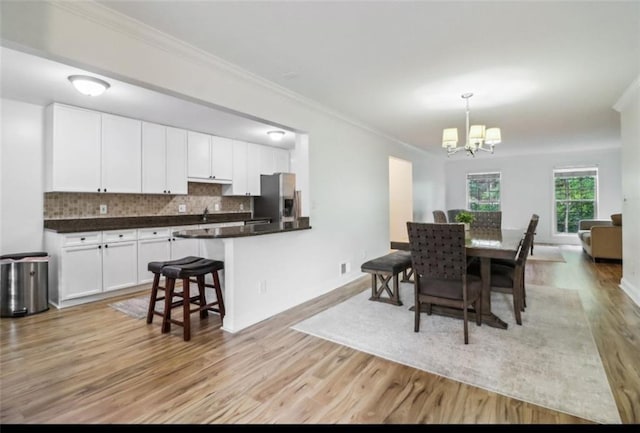 dining area with an inviting chandelier, light hardwood / wood-style flooring, and crown molding