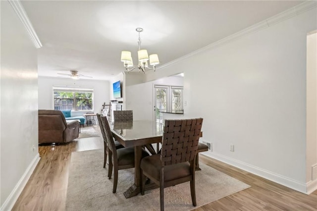 dining area featuring ceiling fan with notable chandelier, light hardwood / wood-style floors, and ornamental molding