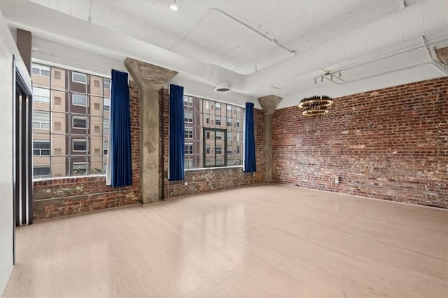 spare room featuring hardwood / wood-style floors and brick wall