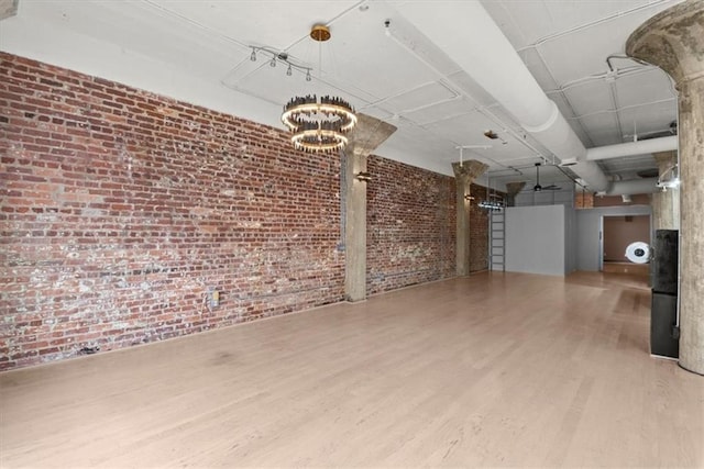 basement with a notable chandelier, wood-type flooring, and brick wall