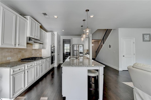 kitchen featuring visible vents, under cabinet range hood, backsplash, white cabinetry, and stainless steel appliances
