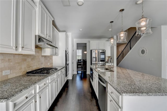 kitchen featuring under cabinet range hood, dark wood finished floors, appliances with stainless steel finishes, white cabinetry, and a sink