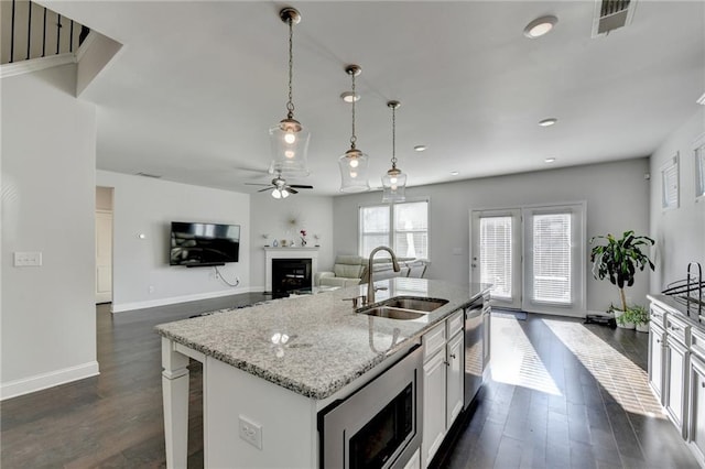 kitchen with a fireplace, stainless steel appliances, dark wood-style flooring, and a sink