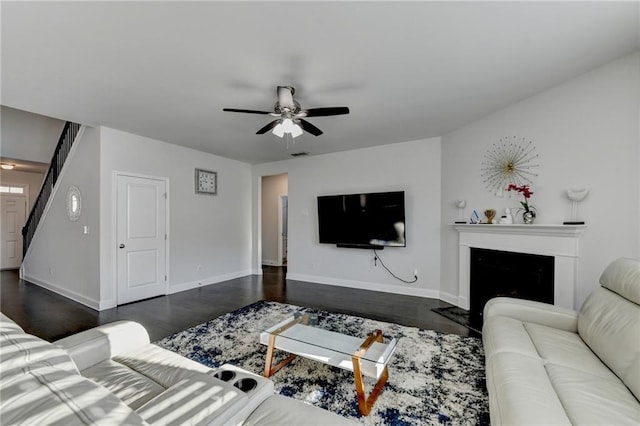 living area featuring visible vents, baseboards, dark wood finished floors, a fireplace with flush hearth, and ceiling fan