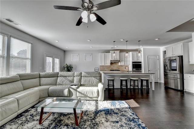 living room with a ceiling fan, recessed lighting, dark wood-style floors, and visible vents