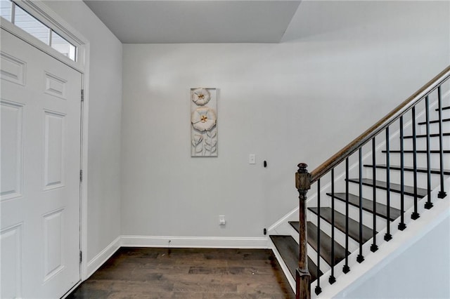 foyer entrance with dark wood-type flooring, stairway, and baseboards