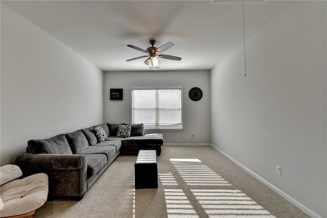 carpeted living area featuring baseboards, attic access, and a ceiling fan