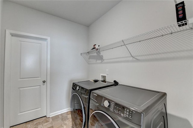 washroom with laundry area, stone finish flooring, baseboards, and washer and clothes dryer