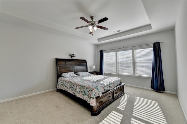 bedroom with a tray ceiling, baseboards, carpet floors, and visible vents