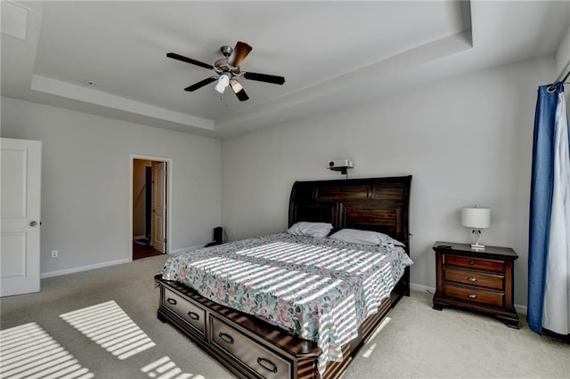 bedroom with light carpet, ceiling fan, a raised ceiling, and baseboards