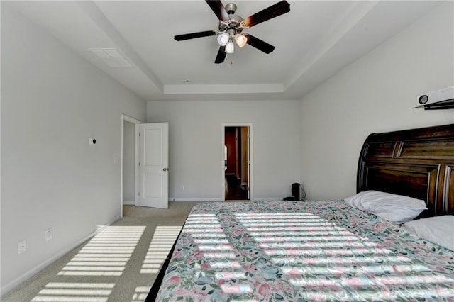 bedroom featuring ceiling fan, a tray ceiling, baseboards, and light carpet