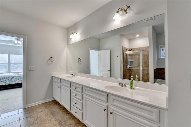 bathroom featuring a sink, baseboards, double vanity, and a shower stall
