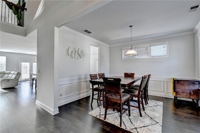 dining room with a wainscoted wall, dark wood-style floors, visible vents, and ornamental molding