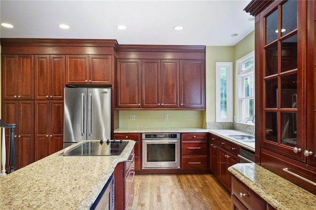 963 Bolingbrook Dr SW, Marietta, GA 30064 - kitchen with appliances with stainless steel finishes, a sink, dark brown cabinets, light wood-type flooring, and light stone counters