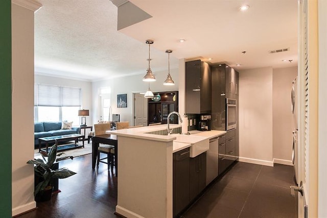 kitchen with appliances with stainless steel finishes, pendant lighting, sink, kitchen peninsula, and a textured ceiling