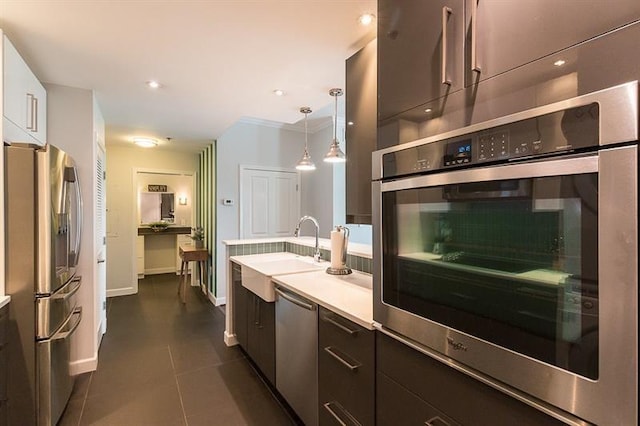 kitchen featuring stainless steel appliances, decorative light fixtures, sink, and dark tile patterned floors