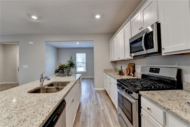 kitchen with sink, stainless steel appliances, white cabinets, and light stone counters