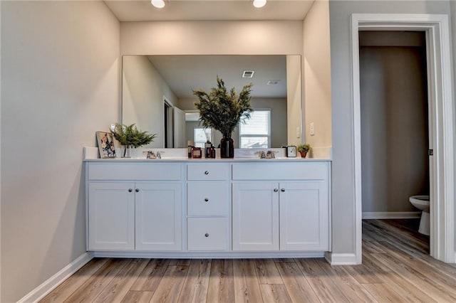 bathroom with toilet, wood-type flooring, and vanity