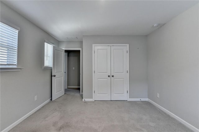 unfurnished bedroom with a closet and light carpet